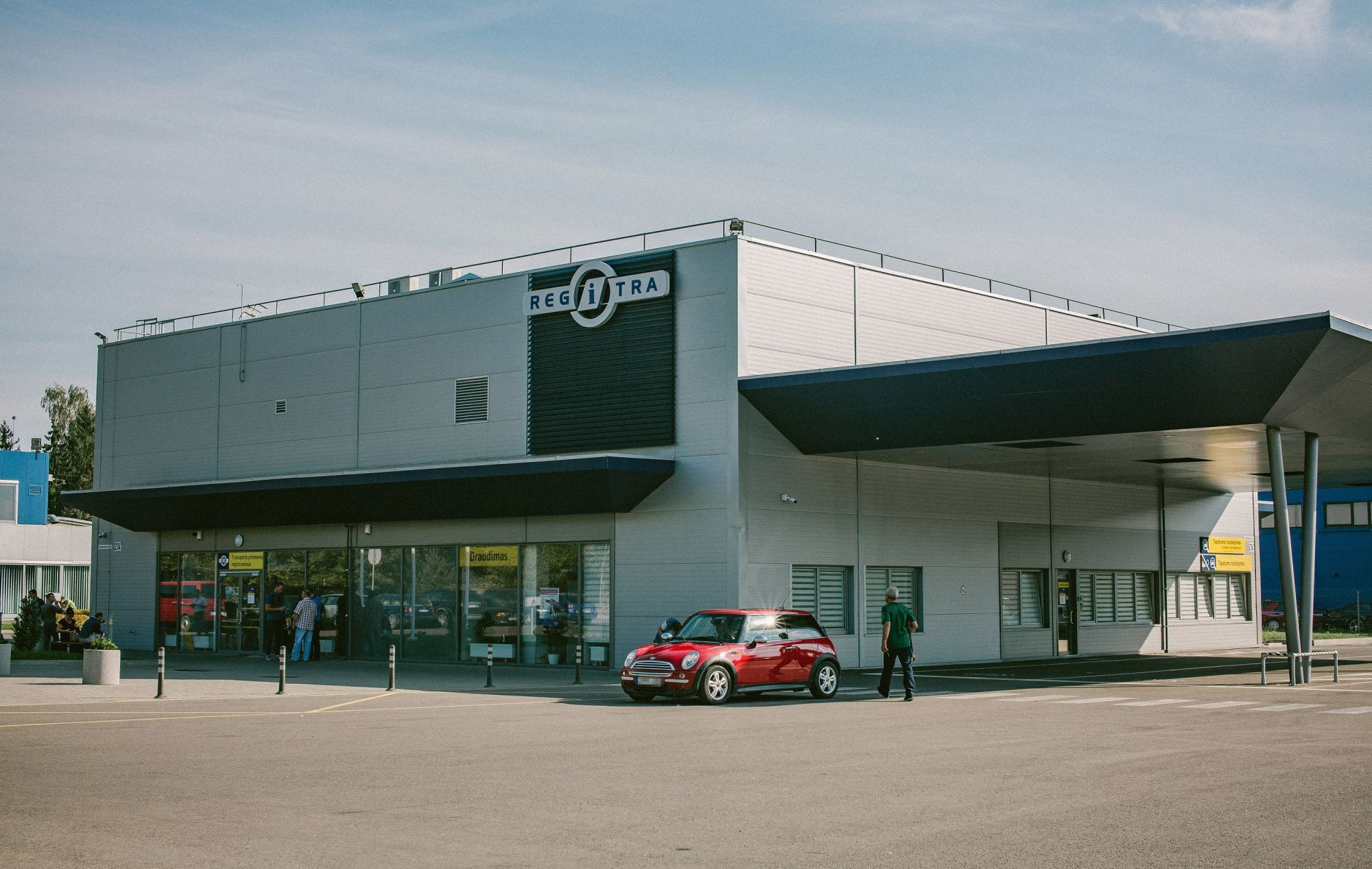 Modernus Regitros padalinys, šalia stovi raudonas naujas automobilis