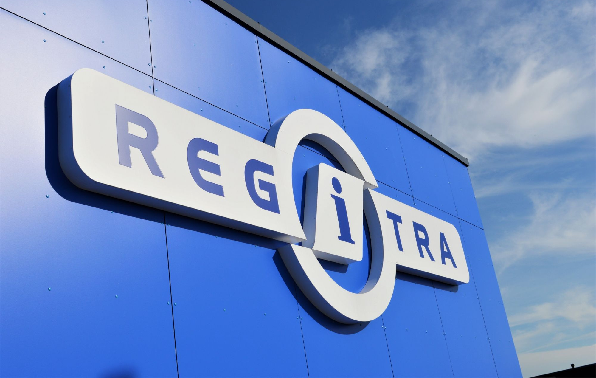 Regitros logotipas ant pastato mėlyname fone.