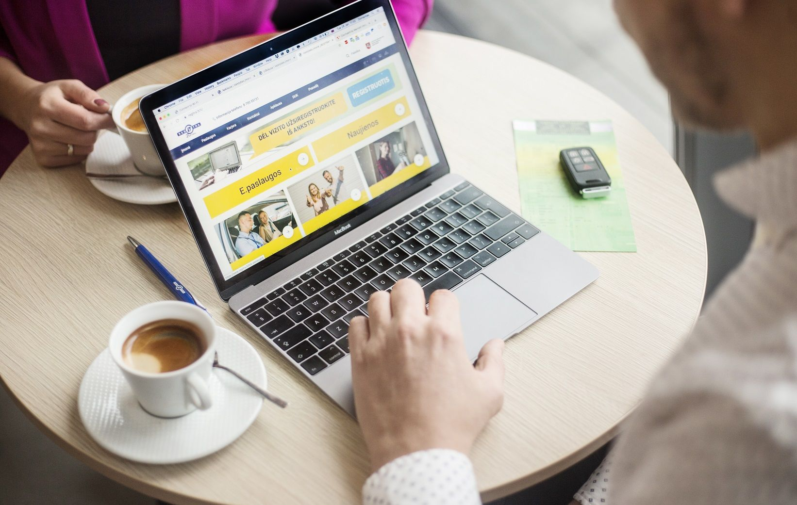 Nuotraukoje matomas žmogus, naudojantis „MacBook“ nešiojamąjį kompiuterį. Ekrane atidaryta svetainė lietuvių kalba, kurioje matyti tokie tekstai kaip: „PASIKEISKITE VAIRUOTOJO PAŽYMĖJIMĄ INTERNETU!“ „E.paslaugos“ „Naujienos“