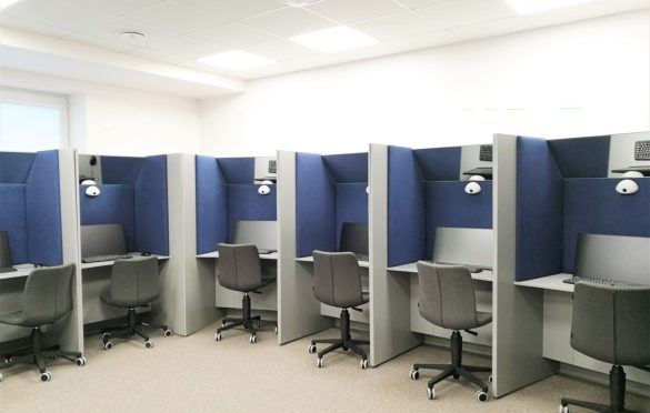 Biuro ar mokymosi erdvė su atskiromis darbo vietomis – kiekviena su stalu, kėde ant ratukų, lempa ir pilkai mėlynomis pertvaromis.