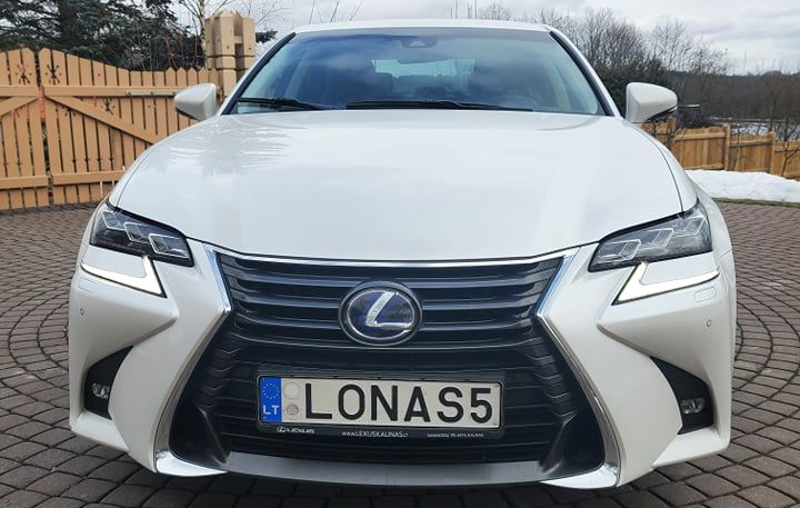 Baltas „Lexus“ automobilis su lietuviškais numeriais „LONAS5“, stovintis kieme prie medinės tvoros.
