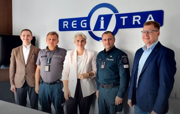 Penki asmenys stovi priešais užrašą „REGITRA“ – trys vilki policijos uniformas su užrašu „POLICIJA“, du apsirengę verslo apranga.