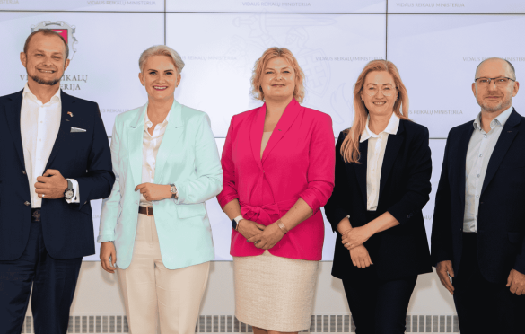 Penki asmenys stovi prieš foną su užrašais „Vilniaus miesto savivaldybė“ ir „Vilniaus miesto ministerija“; visi vilki oficialius drabužius.