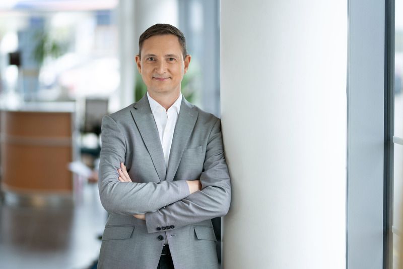 Vyras su pilku kostiumu sukryžiavęs rankas