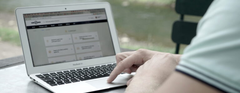 Šioje nuotraukoje matomas asmuo, naudojantis MacBook Air nešiojamąjį kompiuterį. Ekrane atidaryta Regitros svetainė.