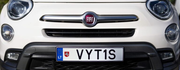 Šioje nuotraukoje matomas baltas Fiat automobilis iš priekio. Valstybinis numeris – „VYT1S“, o kairėje pusėje yra Lietuvos vėliava ir šalies kodas „LT“, kaip įprasta Europos Sąjungos numeriams.