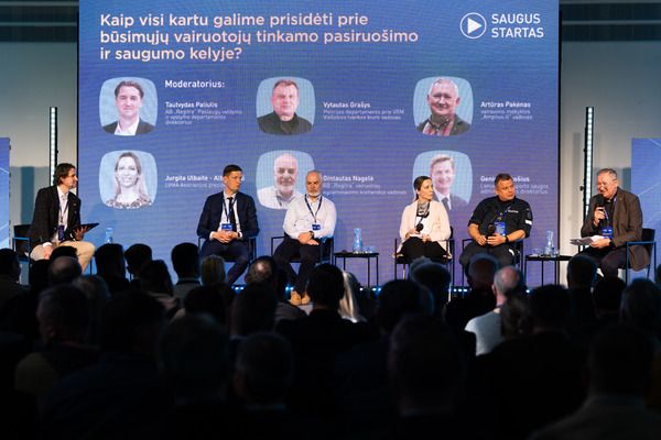 Diskusijos panelė su šešiais dalyviais scenoje prieš auditoriją. Fone – didelis ekranas su tekstu lietuvių kalba apie būsimų vairuotojų pasiruošimą ir saugumą, bei dalyvių vardais. Viršuje matomas „Saugus Startas“ logotipas.