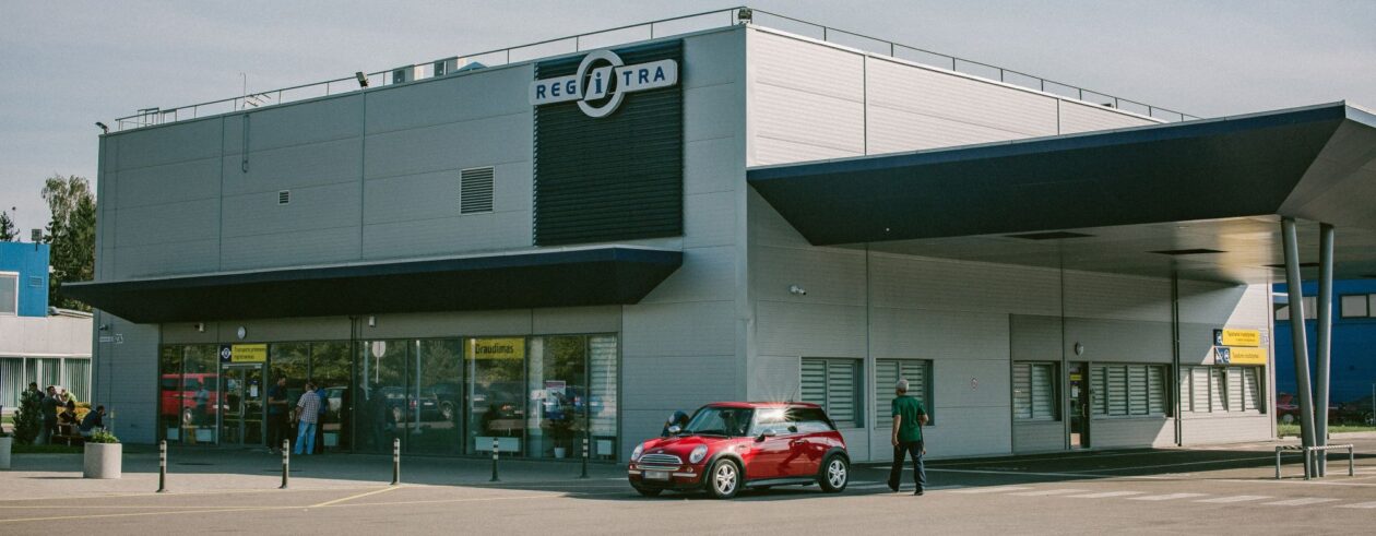 Modernus Regitros padalinys, šalia stovi raudonas naujas automobilis