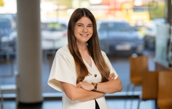 Moteris su ilgais plaukais stovi sukryžiavusi rankas