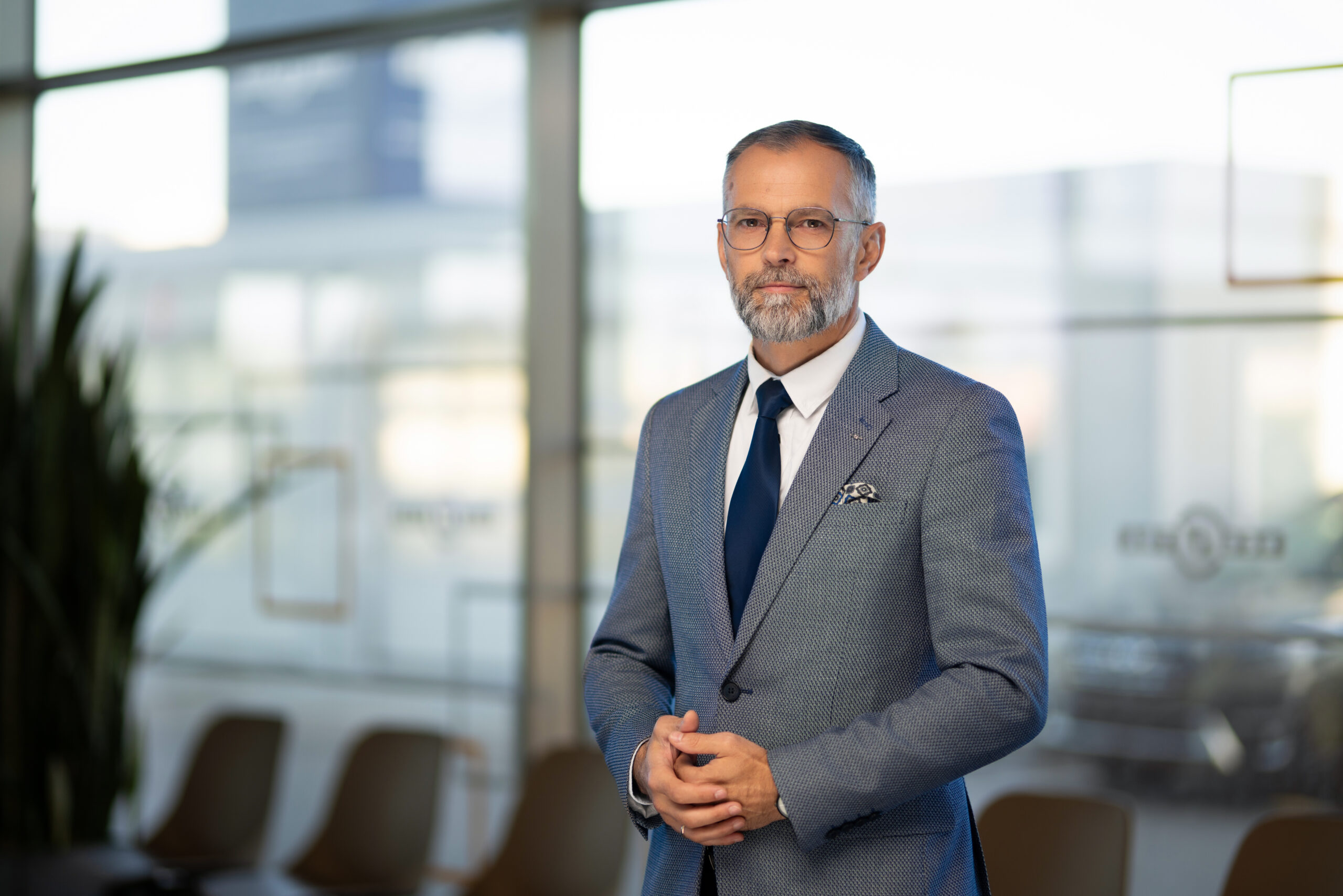 vyras su kostiumu, akiniais ir kaklaraiščiu