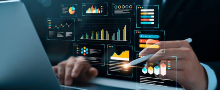 Žmogus dirba prie nešiojamojo kompiuterio, o priešais ekraną matomi skaitmeniniai duomenų analizės grafikai ir diagramos; rankoje laikomas rašiklis, kuriuo rodoma į interaktyvius rodiklius.