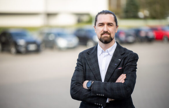 vyras sunėręs rankas stovi prieš automobilių eilę