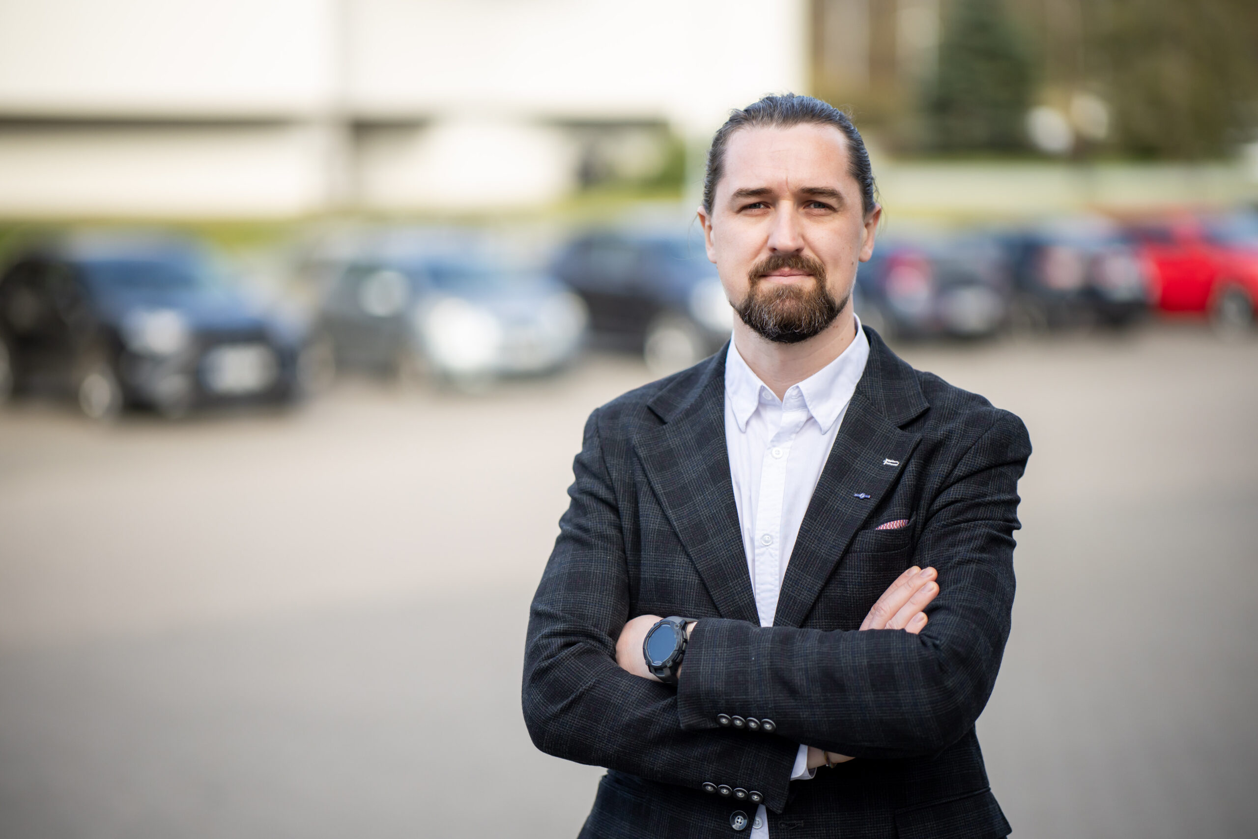 vyras sunėręs rankas stovi prieš automobilių eilę