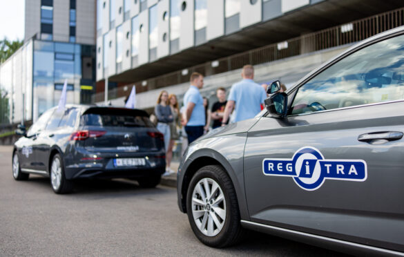 Automobilis ir fone stovintys žmonės