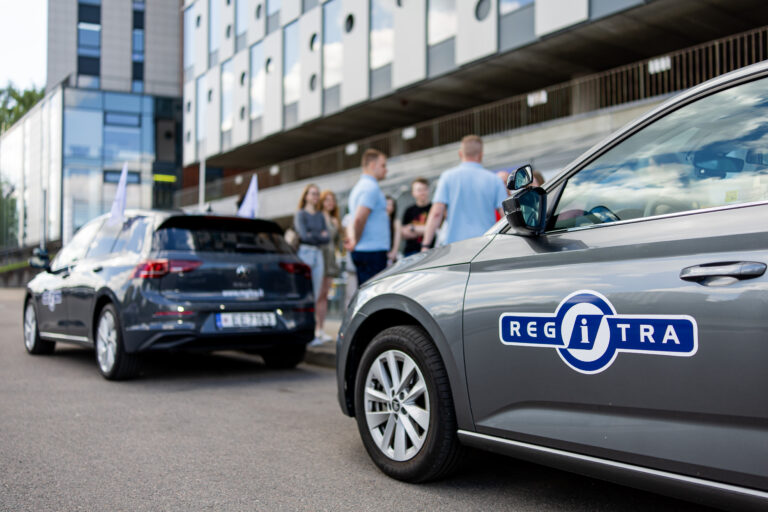 Automobilis ir fone stovintys žmonės